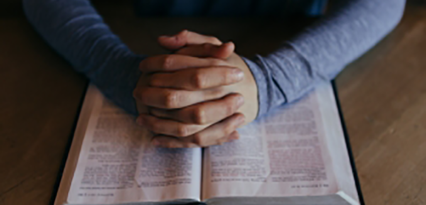 Hand praying and Bible